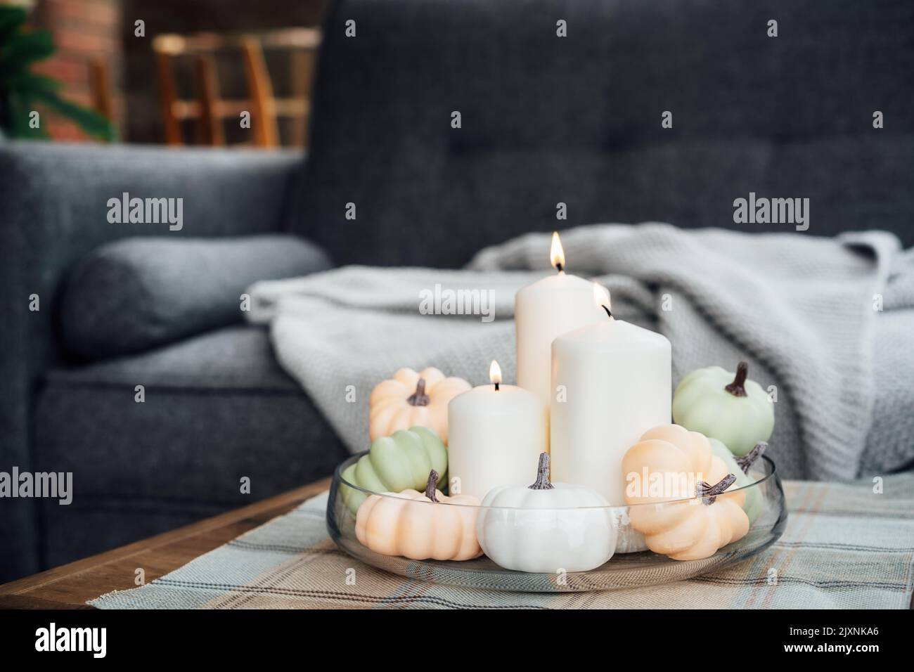 Automne, automne ambiance chaleureuse décor composition pour la maison de l'hygge. Citrouilles décoratives et bougies blanches sur le plateau en verre de la table à café dans le li Banque D'Images Automne, automne ambiance chaleureuse décor composition pour la maison de l'hygge. Citrouilles décoratives et bougies blanches sur le plateau en verre de la table à café dans le li Banque D'Images