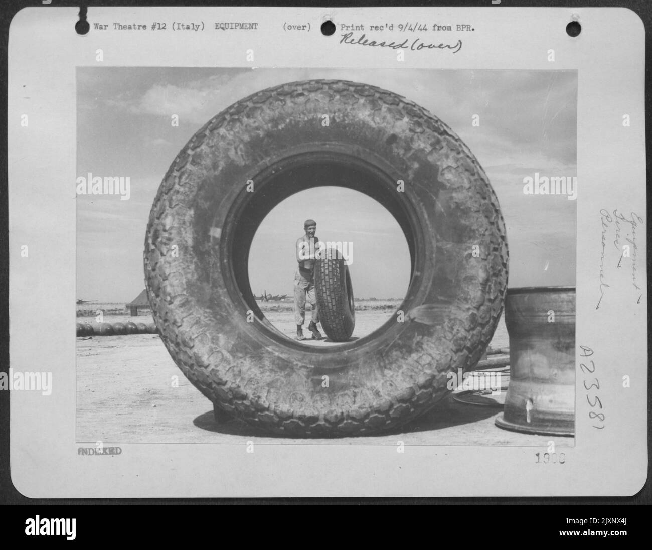 Sgt. R. G. Stallmeyer, 321 Trevor St., Covington, Ky, Un Crewman au sol à Une base Boeing B-17 'Flying Fortress' dans l'AF 15th, en Italie, est encadré par Un 150 Pound Airplane Tyres comme il roule un autre. [La photo montre deux bonnes raisons de rationner les pneus Banque D'Images