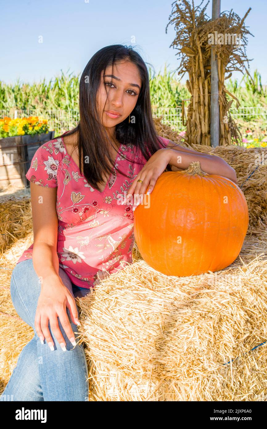 Célébration d'automne Portrait d'une jeune femme asiatique assise sur une chaise de paille avec une citrouille Banque D'Images