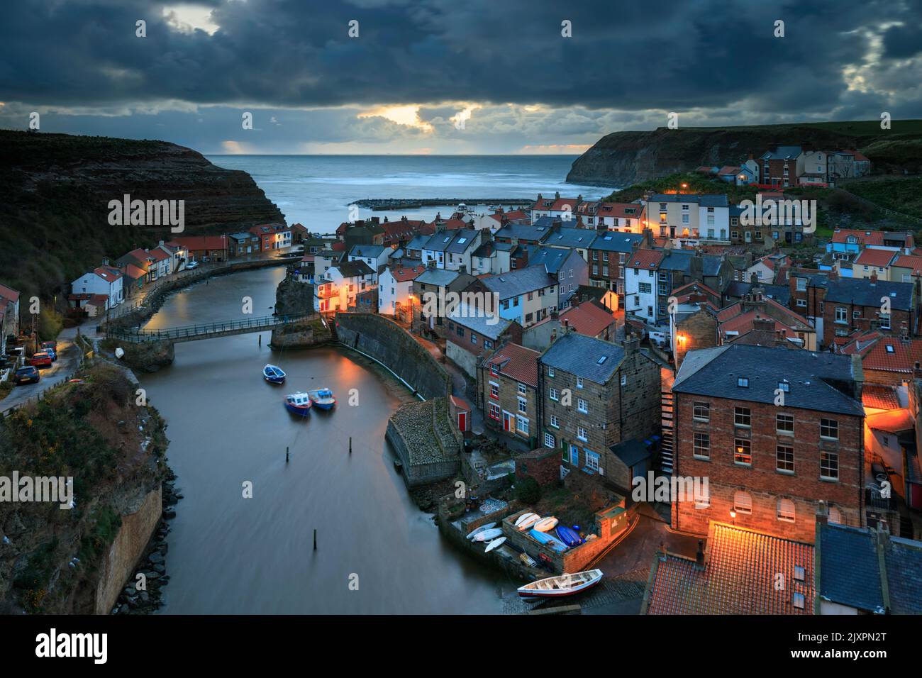 Le village pittoresque de Staithes, sur la côte du Yorkshire du Nord, a été capturé avant le lever du soleil le matin d'une tempête. Banque D'Images
