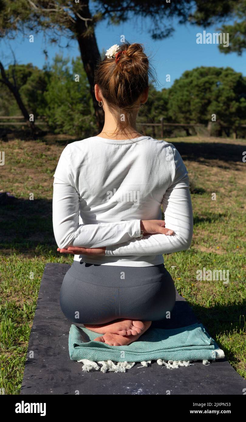 femme vue de derrière faisant le yoga pose avec les bras derrière elle dos dans la nature Banque D'Images