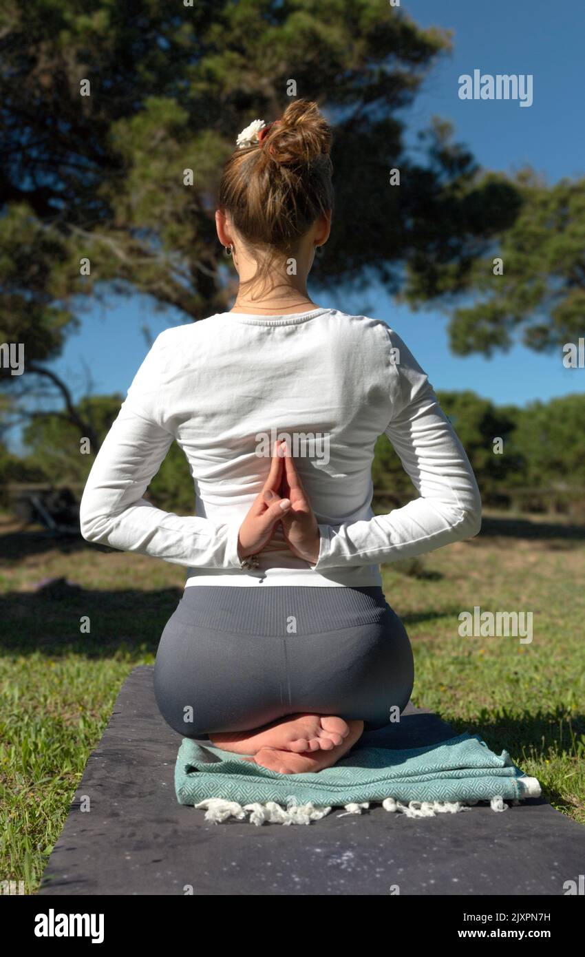 une femme faisant du yoga pose avec les bras derrière elle dans le dos dans la nature Banque D'Images