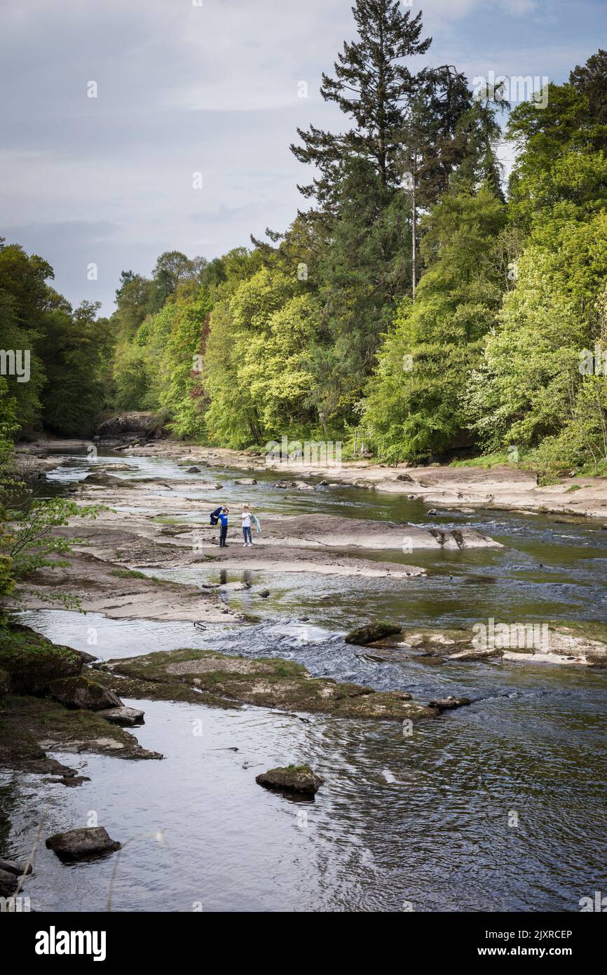 Les enfants jouent sur les rochers exposés de la rivière rapide Ericht, Blairgowrie, Écosse. Banque D'Images