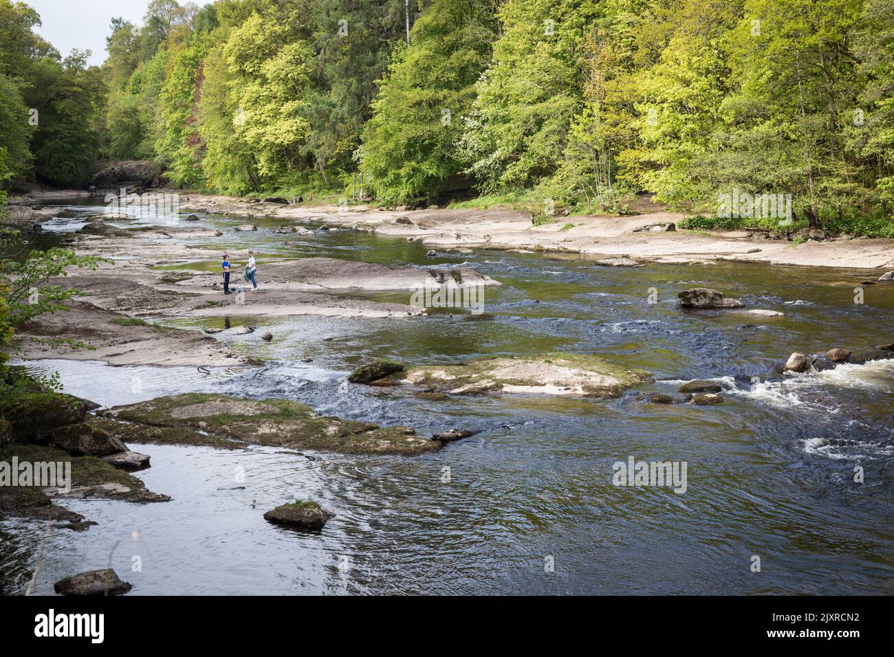 Les enfants jouent sur les rochers exposés de la rivière rapide Ericht, Blairgowrie, Écosse. Banque D'Images