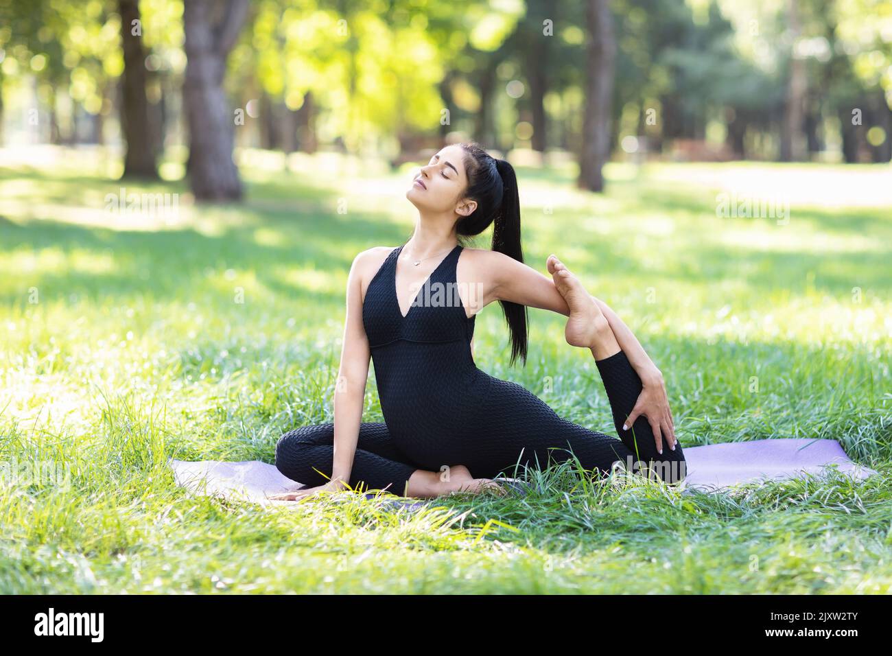 Jeune femme enceinte pratiquant le yoga, faisant une variation de l'exercice Eka Pada Rajakapotasana pigeon pose, l'entraînement dans une couleur noire combinaisons de sport Banque D'Images