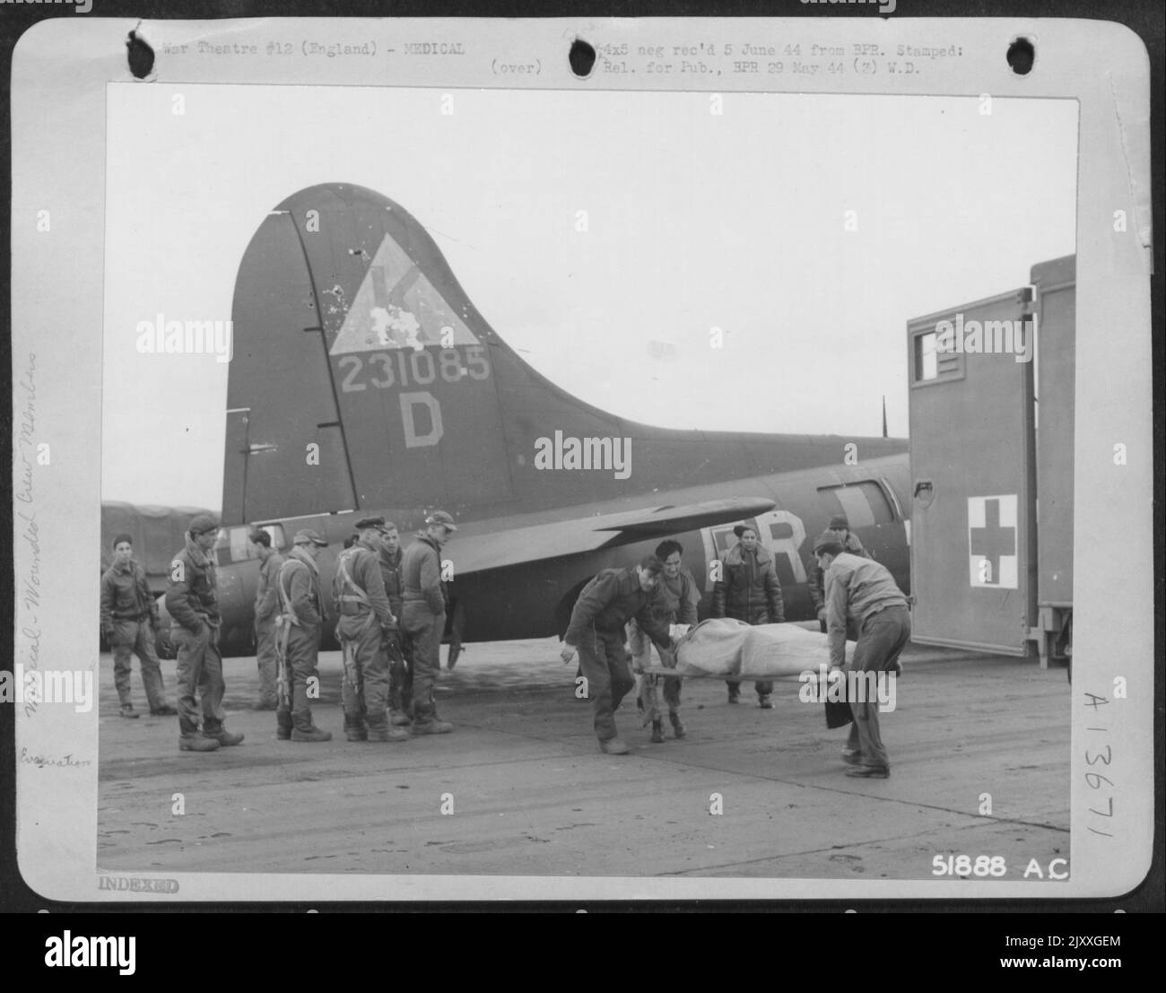 Dans une base d'bombardiers AAF de 8th en Angleterre, un tireur de queue grièvement blessé est transporté d'urgence dans une ambulance d'attente par des corpmen médicaux. Les membres du sol et de l'équipage de conduite regardent. Banque D'Images