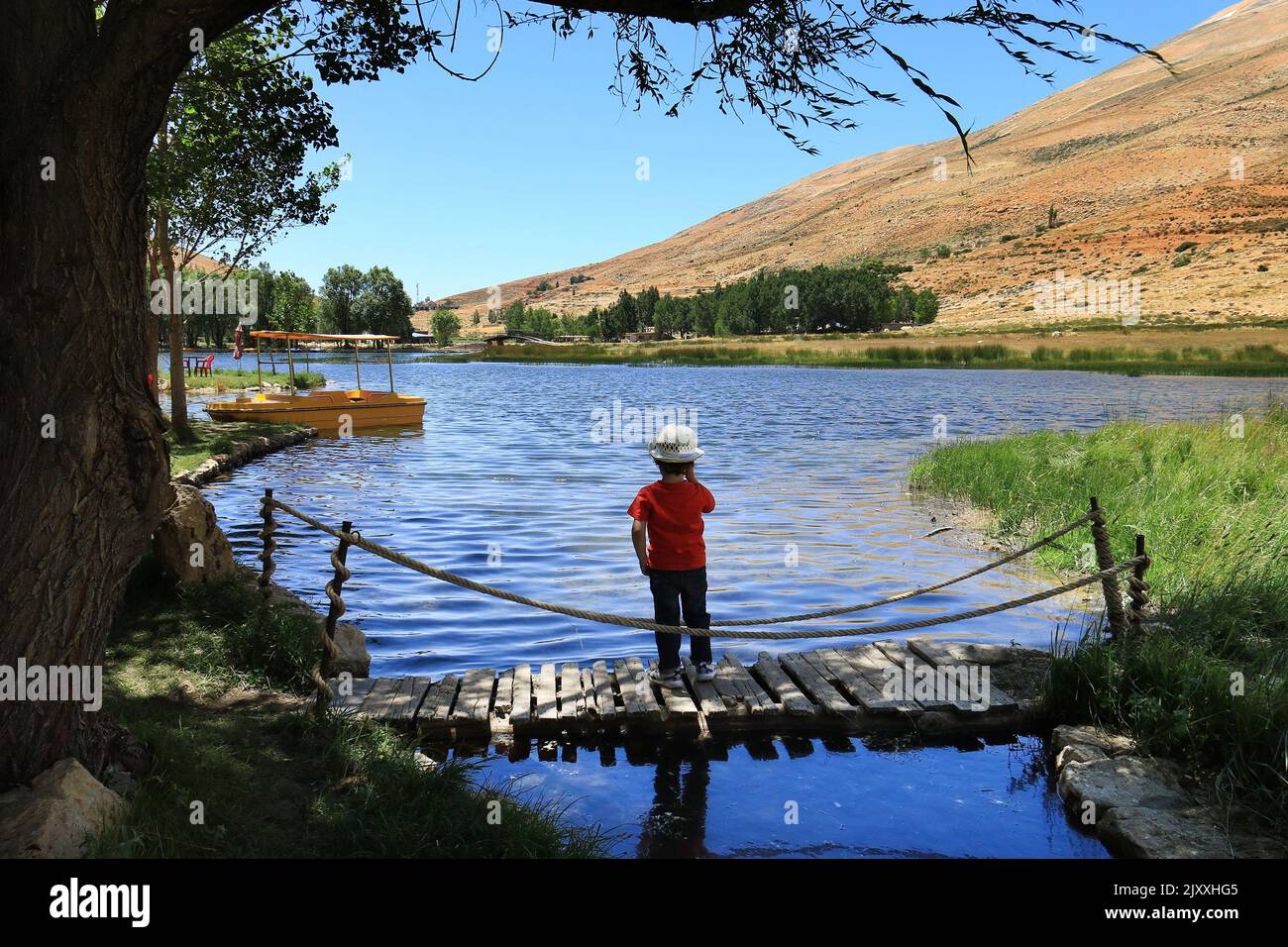 Oyoun Orghosh, Liban - 31 juillet, 2022. Un tout-petit sur un pont en bois qui donne sur un lac. Banque D'Images