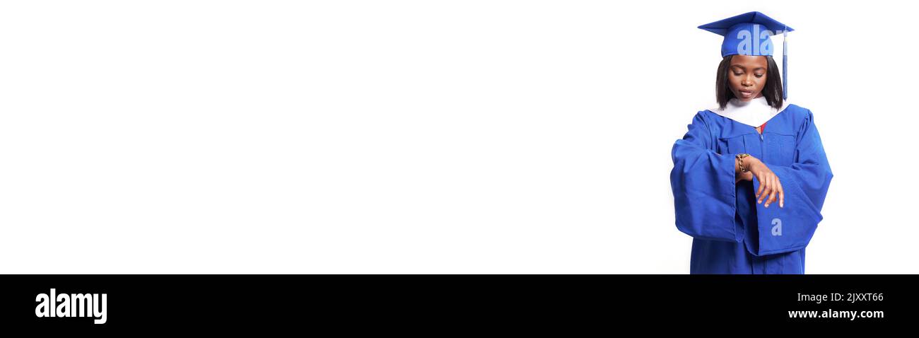 Bannière. Une femme afro-américaine vêtue d'une robe bleue et d'un chapeau sur un fond blanc isolé regarde la montre sur sa main. Le concept de l'éducation, une étudiante de deuxième cycle. Photo de haute qualité Banque D'Images