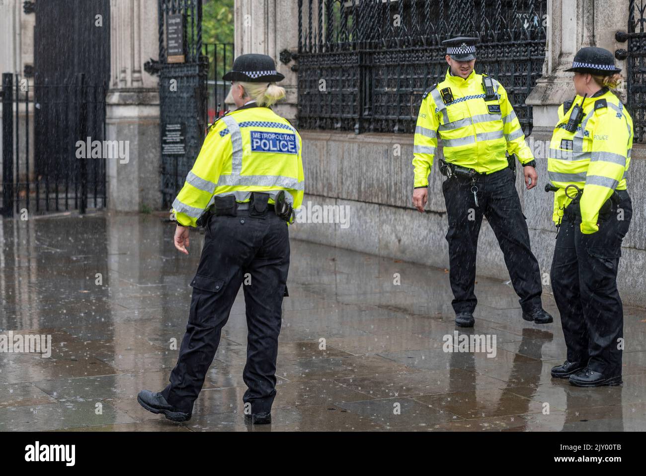 Les policiers en service dans la pluie battante à l'extérieur des chambres du Parlement. Les policiers masculins et féminins sont mouillés par de fortes pluies Banque D'Images
