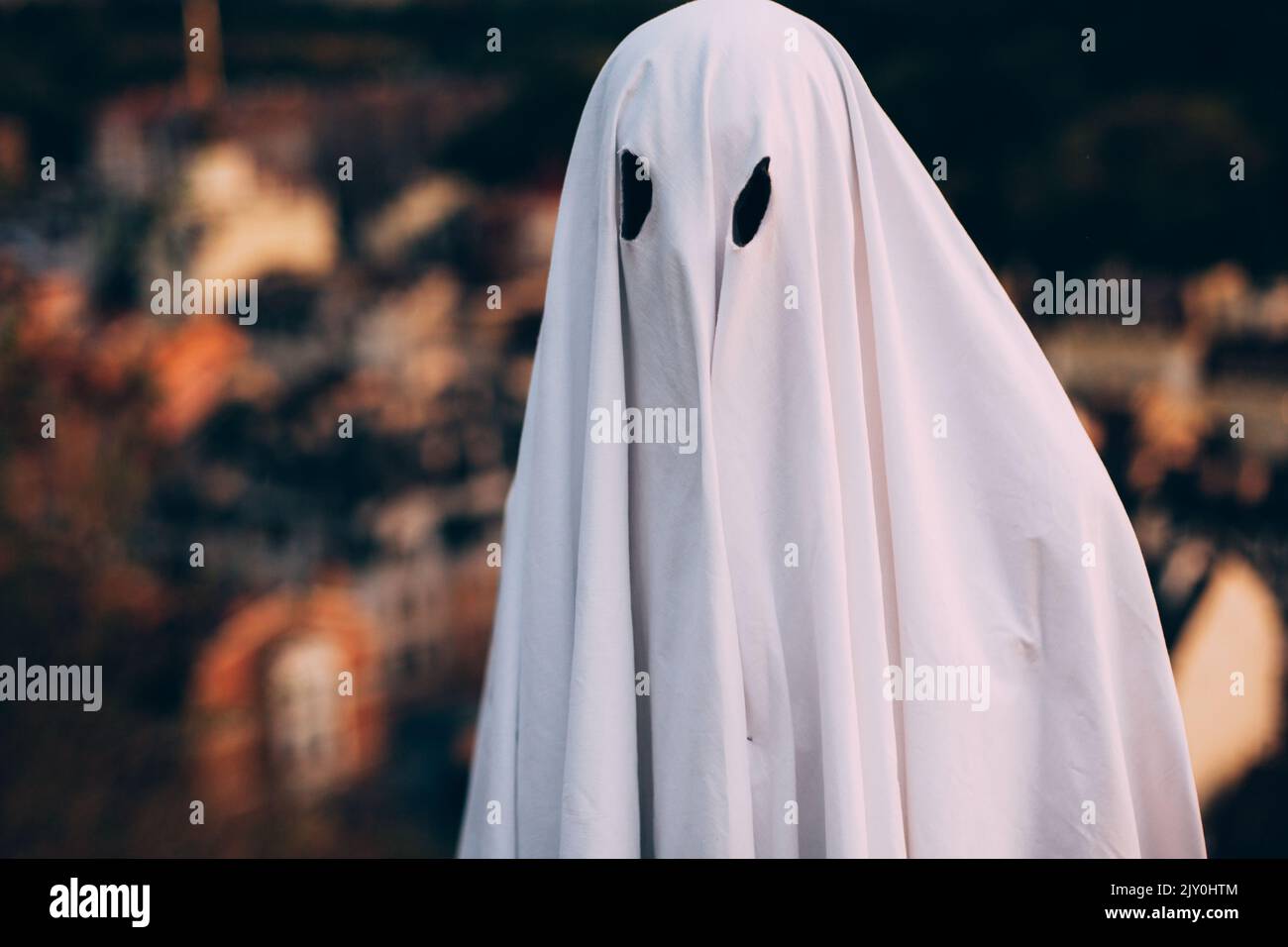 Fantôme debout contre la ville du soir pendant Halloween Banque D'Images