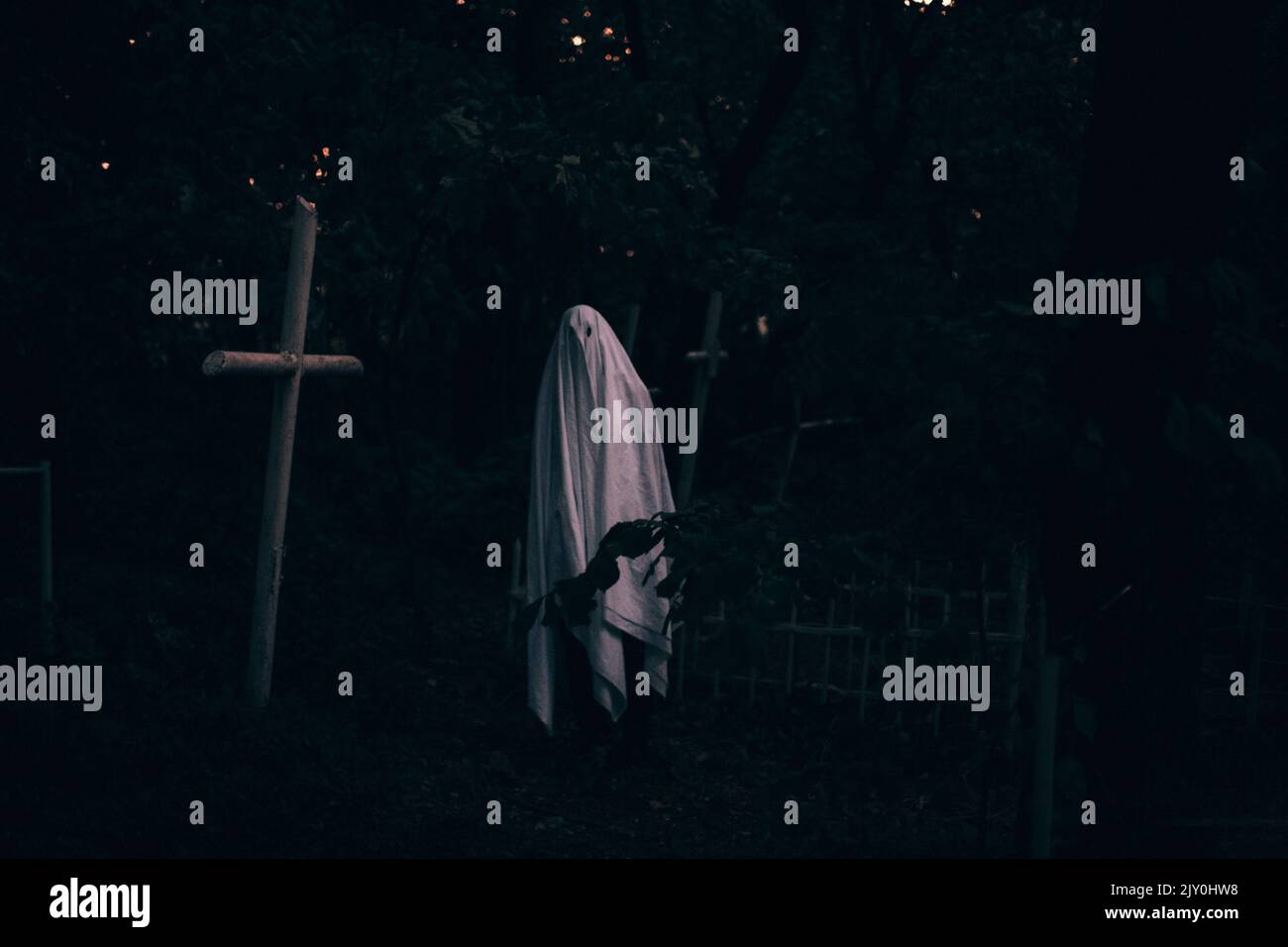 Fantôme dans le cimetière entre les tombes pendant Halloween Banque D'Images