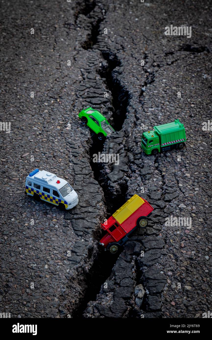Jouets de voiture colorés sur un asphalte fissuré Banque D'Images