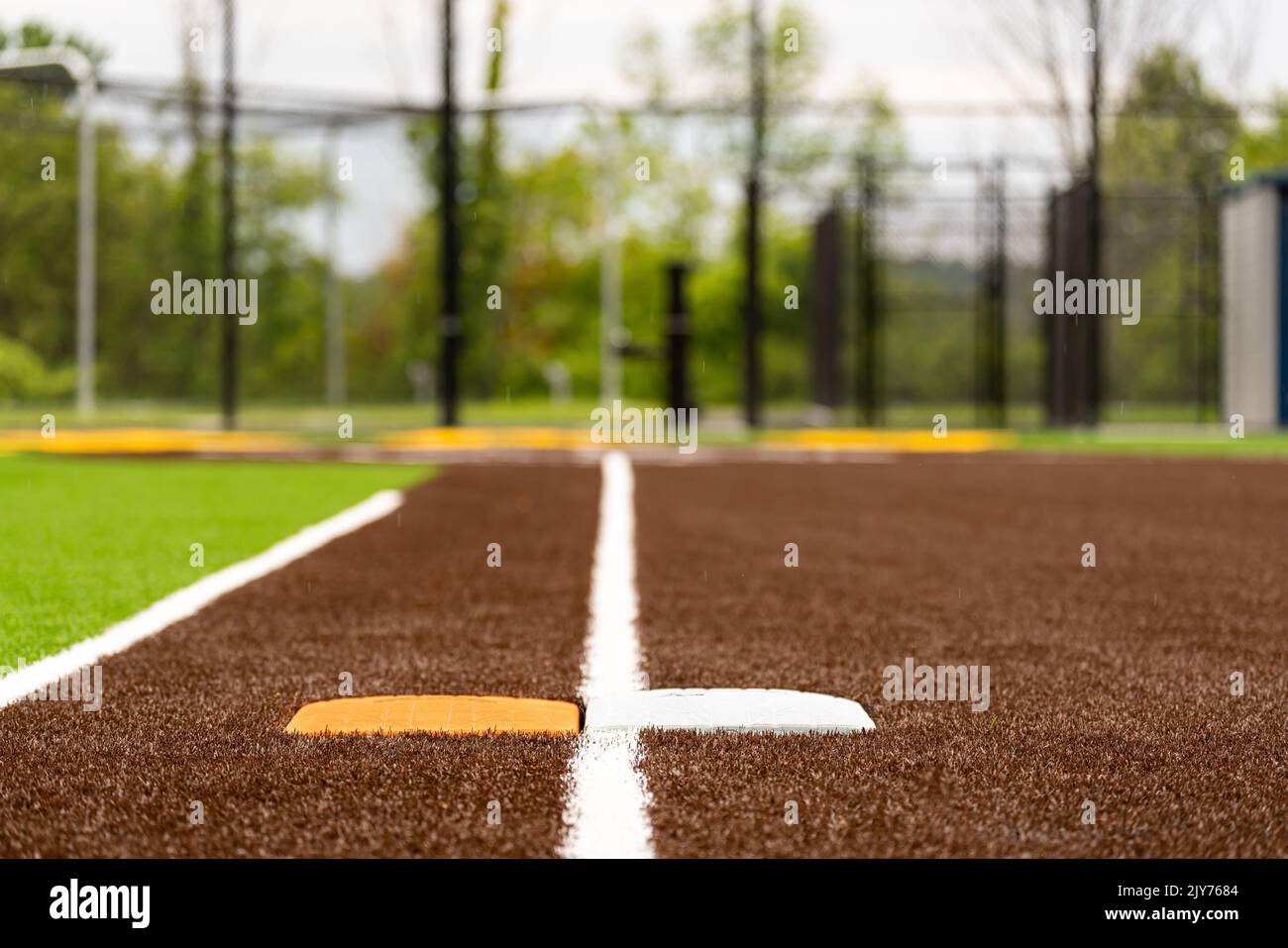 Vue du terrain de softball synthétique pour l'école secondaire, première base avec deuxième base de sécurité orange, en regardant vers la plaque d'accueil. Banque D'Images