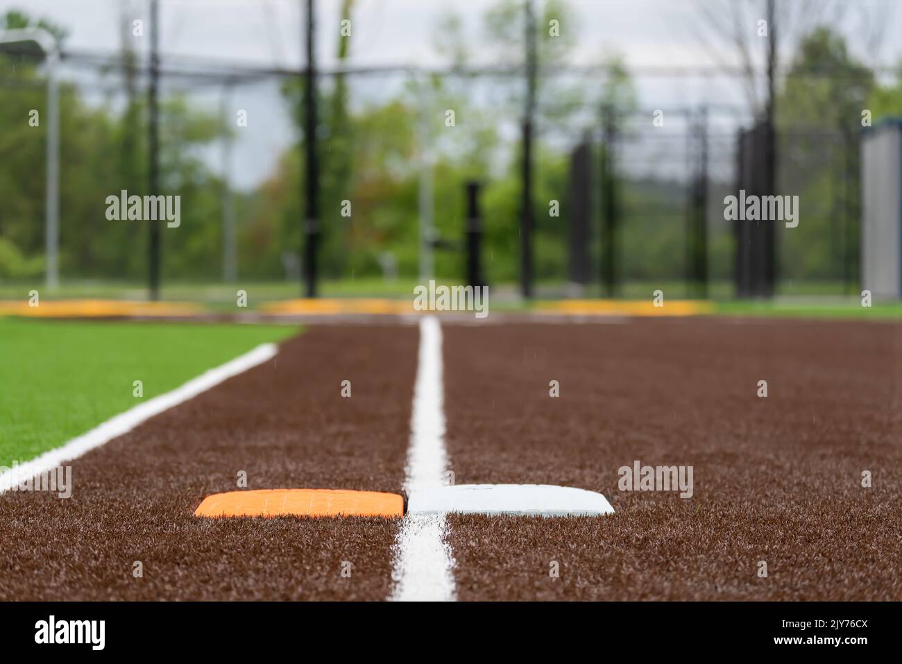 Vue du terrain de softball synthétique pour l'école secondaire, première base avec deuxième base de sécurité orange, en regardant vers la plaque d'accueil. Banque D'Images