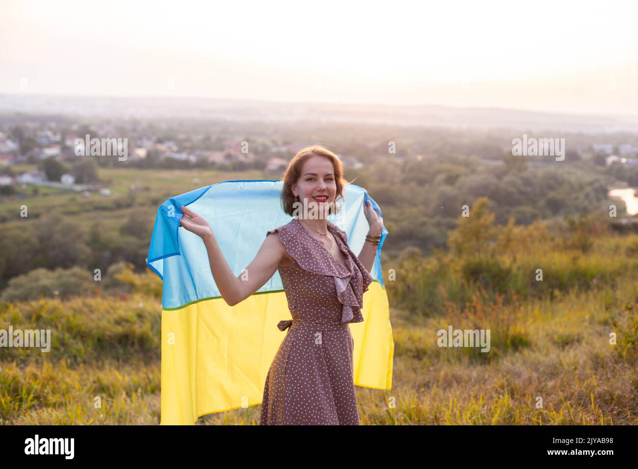 Femme heureuse en robe longue portant un drapeau jaune et bleu de l'Ukraine Banque D'Images