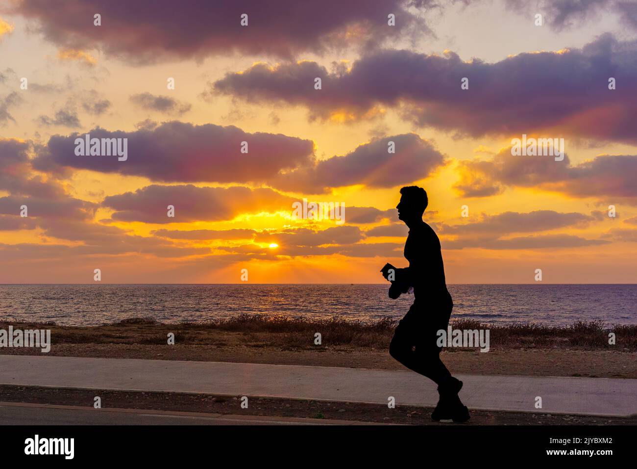 Haïfa, Israël - 05 septembre 2022: Scène de coucher de soleil sur la côte de la mer Méditerranée, avec silhouette de jogger. Haïfa, nord d'Israël Banque D'Images