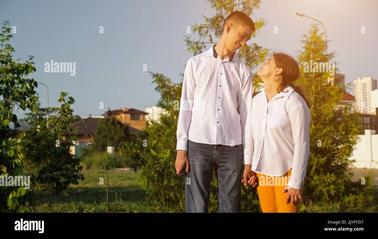La jeune femme et l'homme handicapés tiennent les mains souriantes au coucher du soleil Banque D'Images