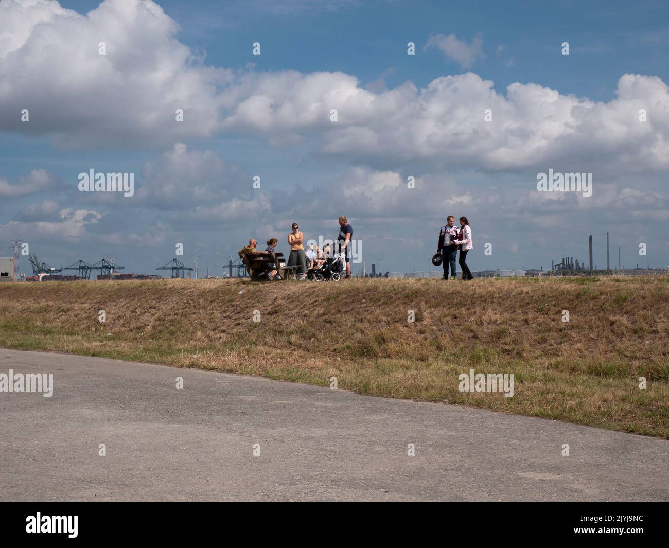 Doel, Belgique, 21 août 2022, les gens marchent sur le remblai de l'Escaut avec un champ de nuages et une industrie spectaculaires en arrière-plan Banque D'Images