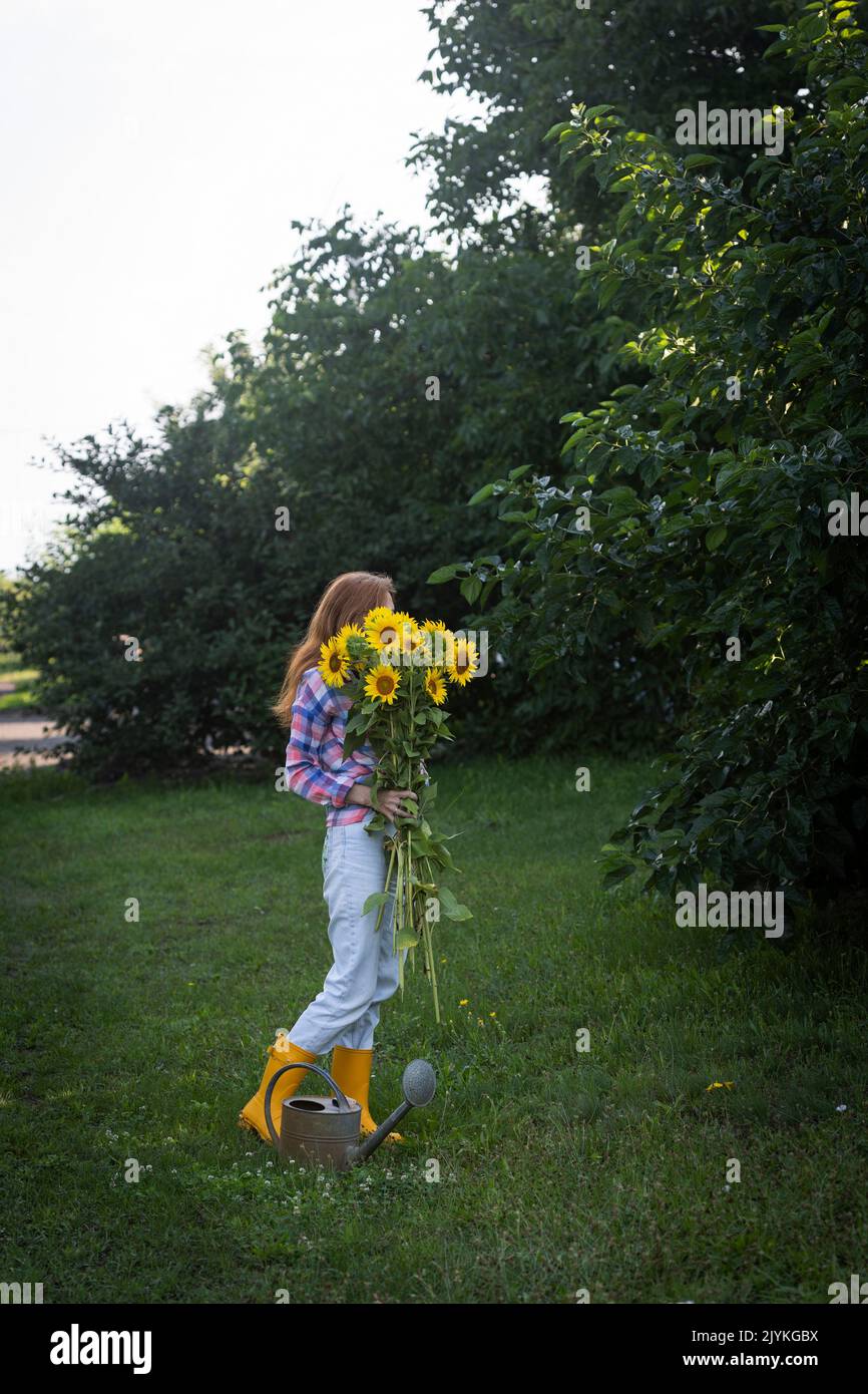 fille tenant un énorme bouquet de tournesols dans leurs mains sur la toile de fond d'un paysage rural Banque D'Images