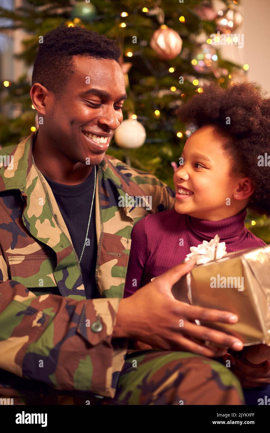 Soldat américain en uniforme à la maison en congé pour Noël donnant à la fille présente Banque D'Images