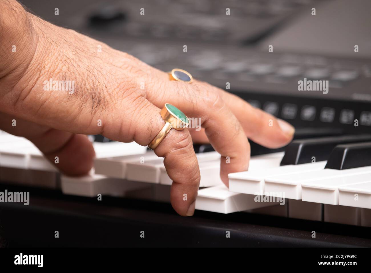 Mains de l'homme portant la Panna naturelle d'Emeraude et le bleu saphir Neelam Gemstone jouant des notes sur le piano ou le clavier. Formation musicale ou coaching, Live Mu Banque D'Images