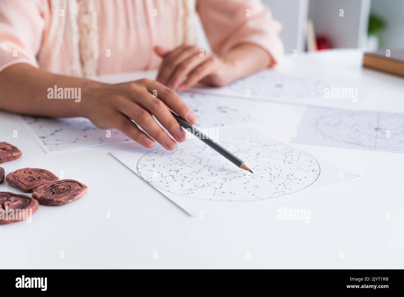 vue rognée de l'astrologue flou pointant sur la carte celestials avec un crayon Banque D'Images