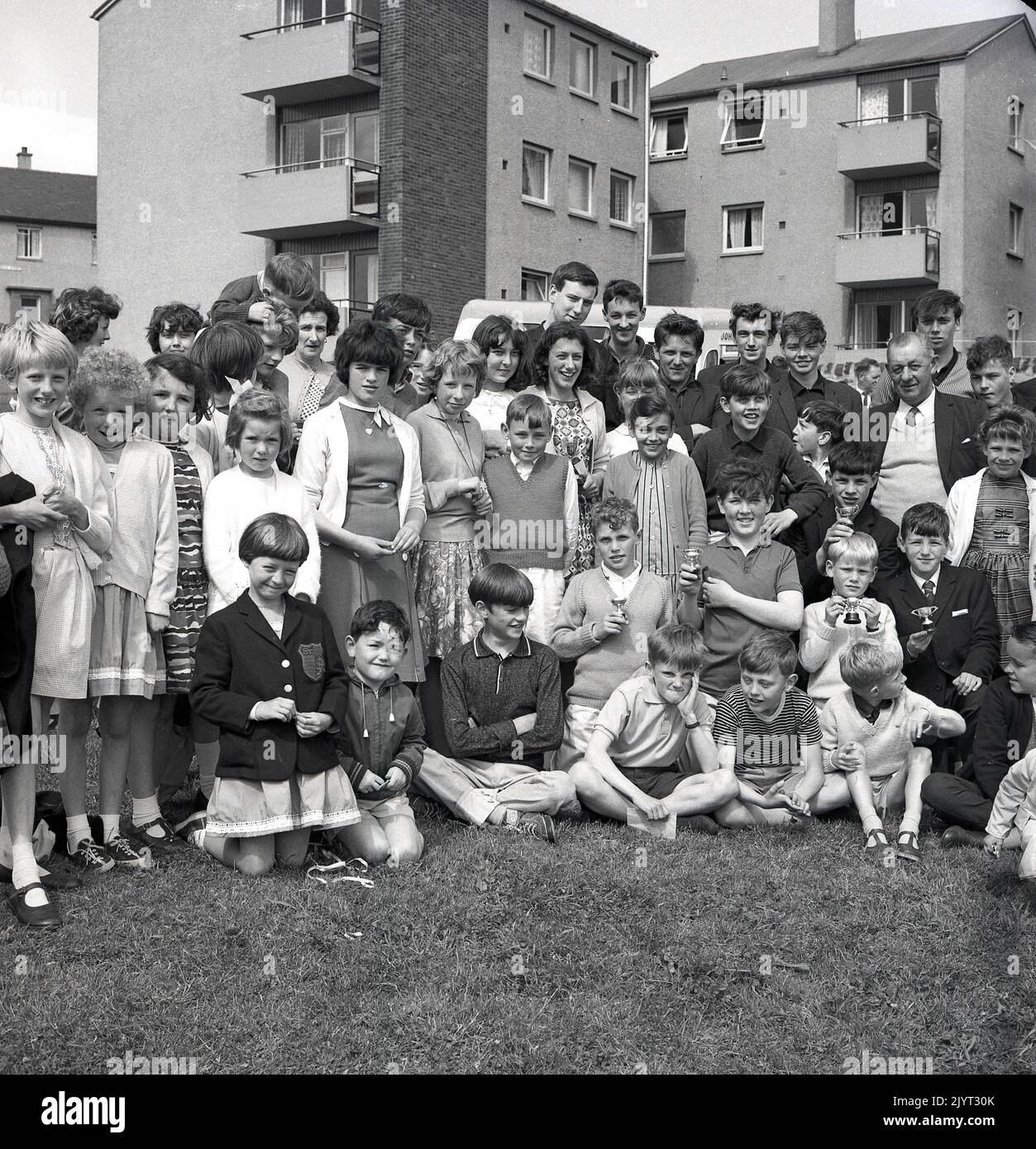 1965, historique, à l'extérieur d'un domaine de logement public, des jeunes se sont réunis pour une photo de groupe, certains tenant des trophées miniatures, après avoir participé au gala du North Queensferry, Fife, Écosse, Royaume-Uni. Banque D'Images