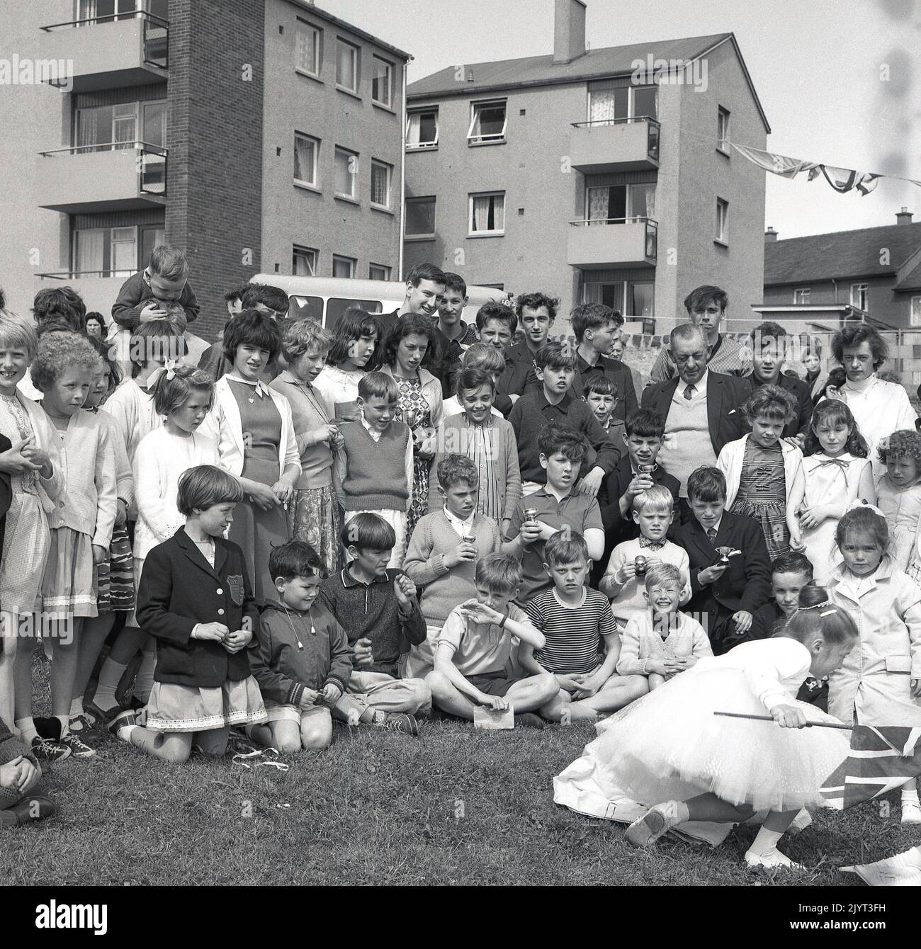 1965, historique, les enfants et les adultes se sont réunis pour une photo de groupe, certains tenant des trophées miniatures, après avoir pris part à la journée de gala du North Queensferry, une journée communautaire pour les résidents du domaine, North Queensferry, Fife, Écosse, Royaume-Uni. Banque D'Images