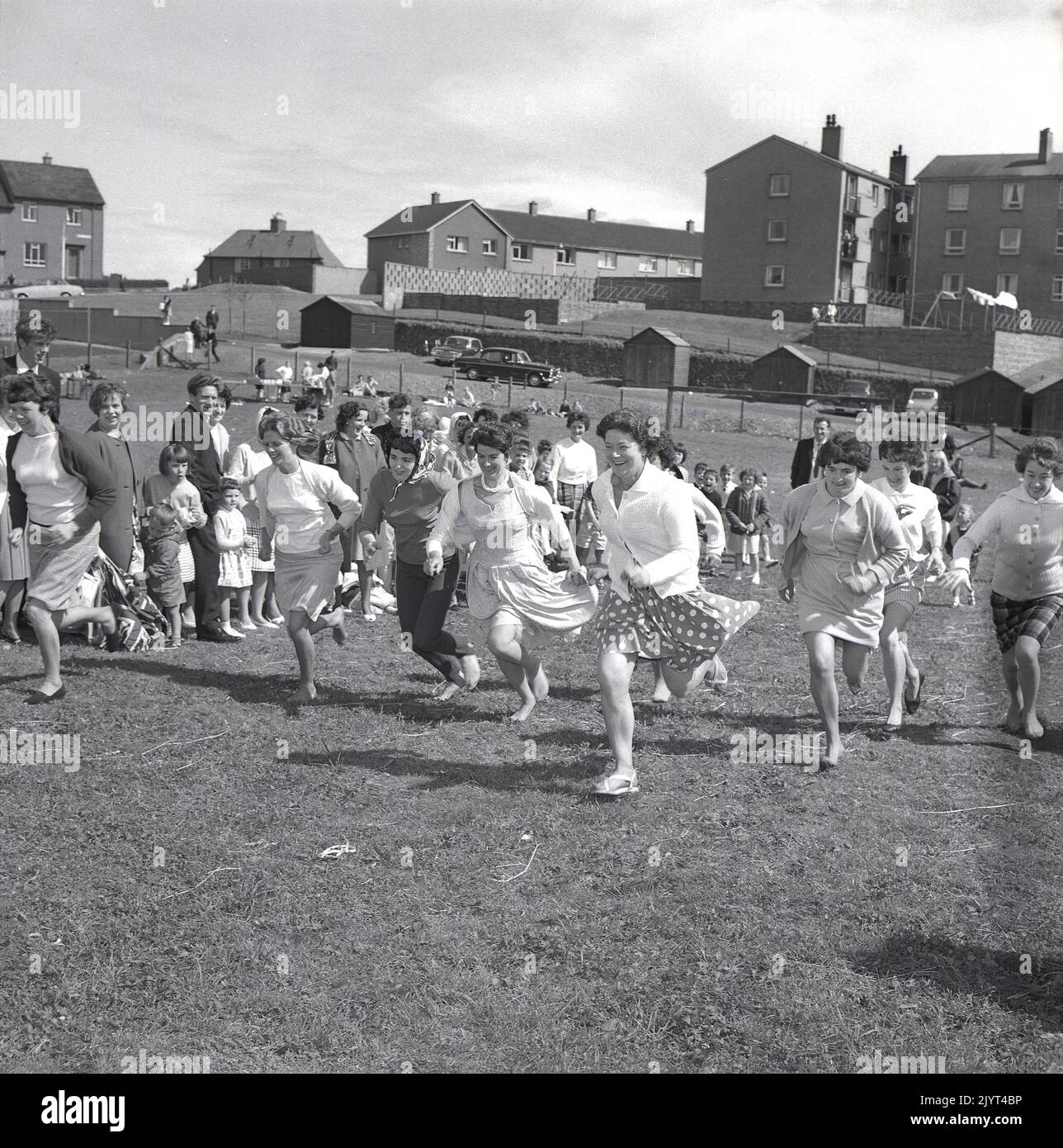 1965, historique, les femmes prenant part à une compétition de course, plusieurs dans les pieds de bareft, sur l'herbe dans un champ dans un domaine d'habitation à North Queensferry, Fife, Écosse, Royaume-Uni, dans le cadre de la journée de gala de North Queensferry. Banque D'Images