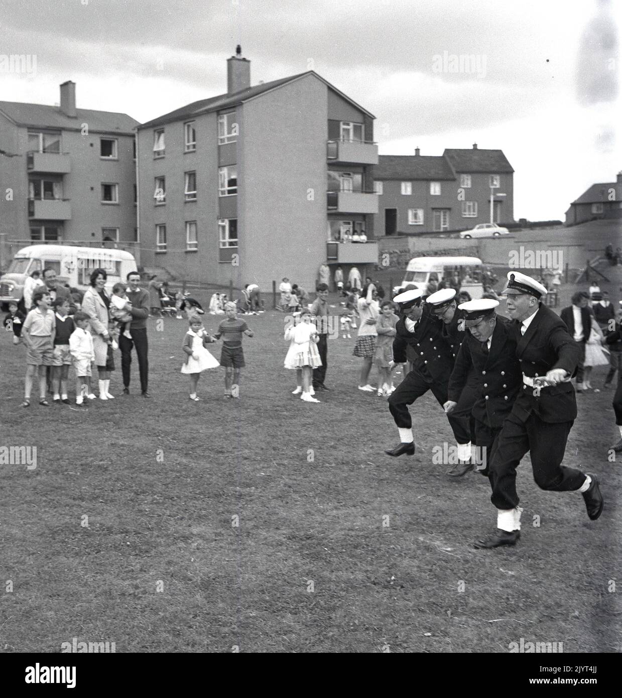 1965, officiers de marine historiques en uniforme participant à une course à trois pattes dans un champ situé dans un domaine de logement à North Queensferry, Edimbourg, Écosse, Royaume-Uni, dans le cadre de la journée de gala du North Queensferry, une journée communautaire pour les résidents du domaine, Banque D'Images