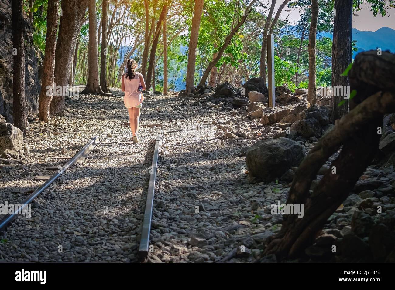 Vue arrière de la jeune fille avec une bouteille d'eau marchant seule dans la forêt sentier nature marcher sur le fond de bois de sentier à Hellfire Pass à Kanchanaburi en Thaïlande Banque D'Images