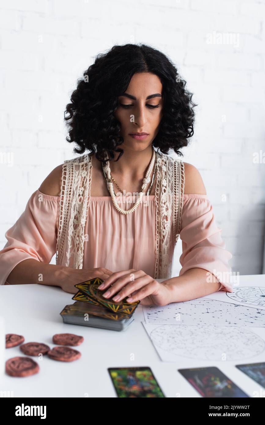 KIEV, UKRAINE - 29 JUIN 2022 : brunette fortune Teller près des cartes de tarot et des cartes célestes Banque D'Images