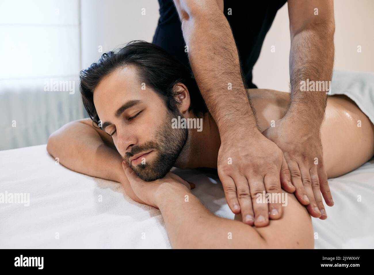 Bel homme bénéficiant d'un massage relaxant lors d'un soin spa dans le centre de bien-être. massothérapie pour client masculin Banque D'Images
