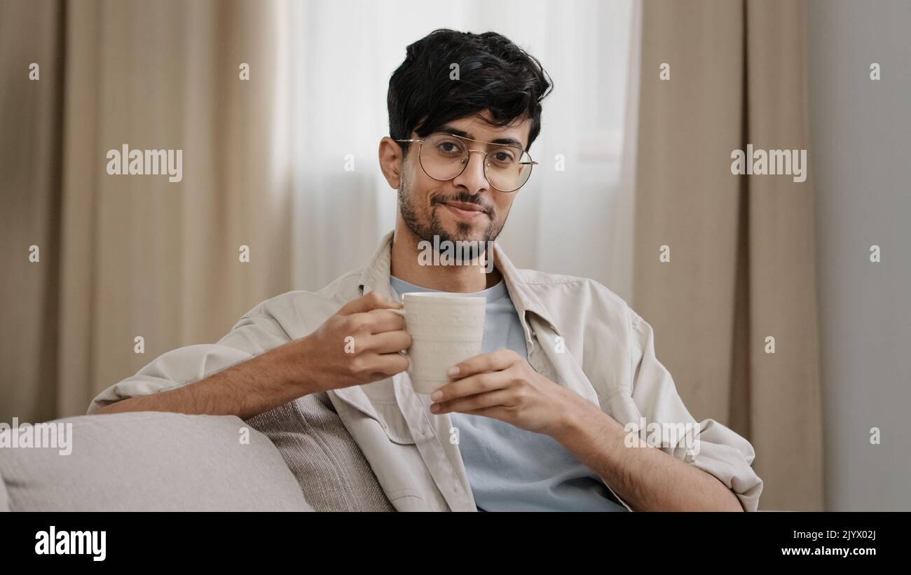 Arabe barbu millennium homme latin dans des verres assis à la maison appréciant délicieux fruits chaud tisane thé café boisson cacao cappuccino Banque D'Images