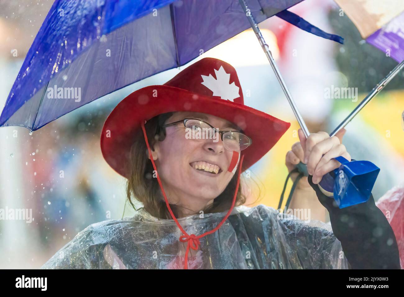 Femme souriante avec un chapeau canadien. Il pleut dans le stade Athlétique des Jeux panaméricains de Toronto, Canada, 2015 Banque D'Images