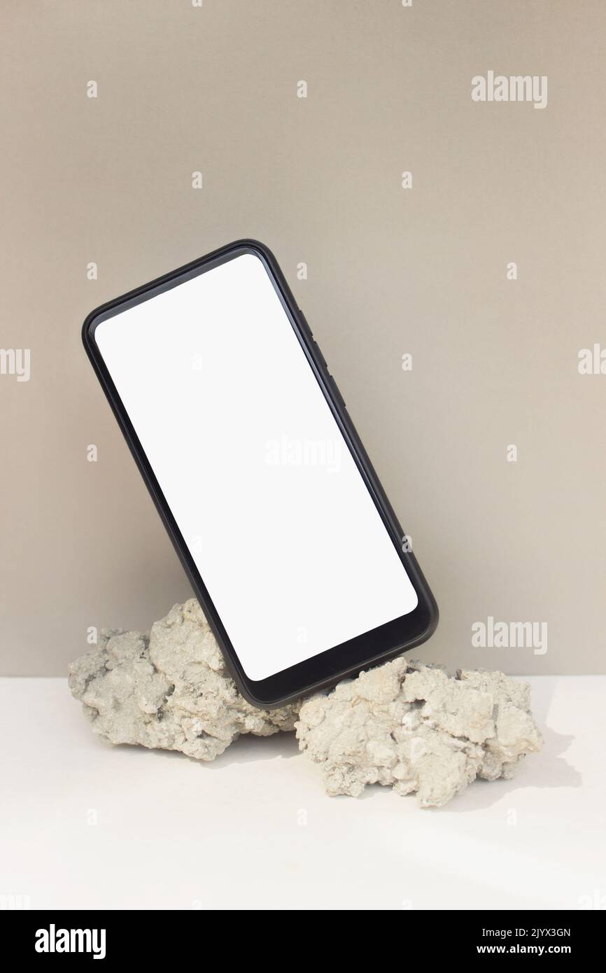 Maquette smartphone équilibre sur pierre naturelle sur fond beige. Téléphone avec modèle d'écran vierge Banque D'Images
