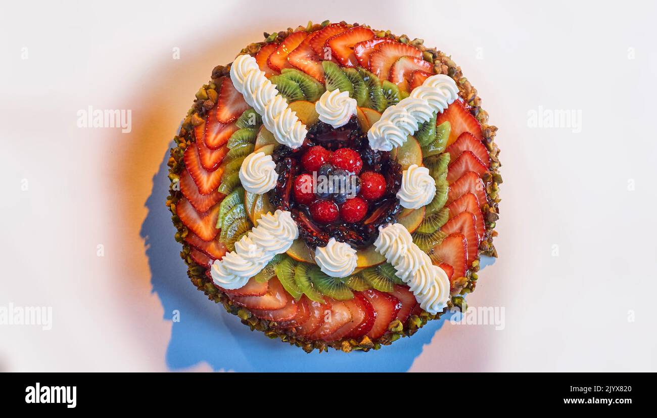 Tarte aux fruits, pâtisserie aux fruits ronde avec croûte de pistache. Crème de noix de coco surmontée d'ananas, de fraises, de kiwi, de mûres, de framboises Banque D'Images