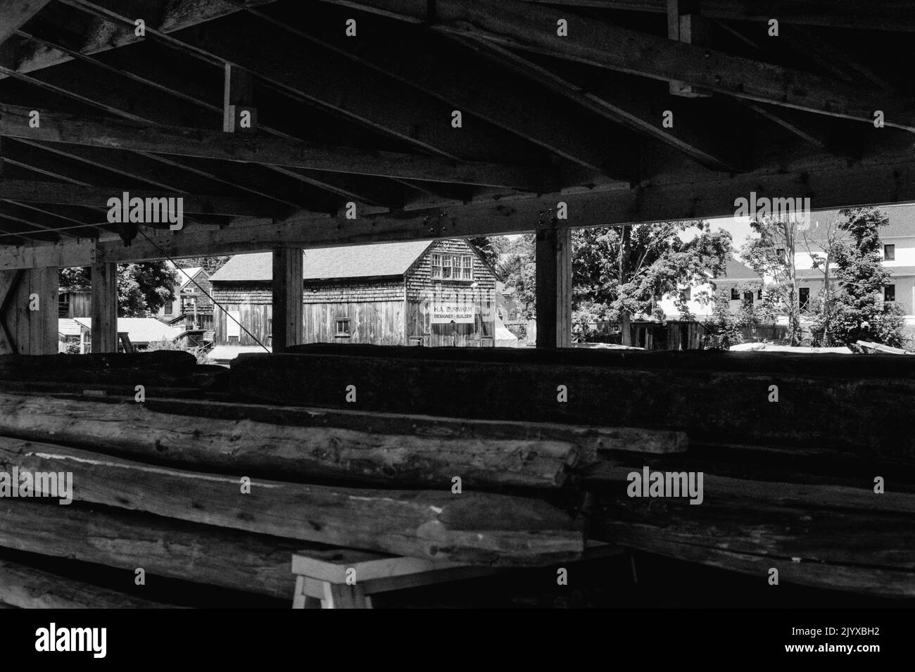 Une vue sur une usine abandonnée avec un panneau indiquant H A Burnham est vue à travers la grange de bois au musée de la construction navale d'Essex - Essex, Massachusetts Banque D'Images