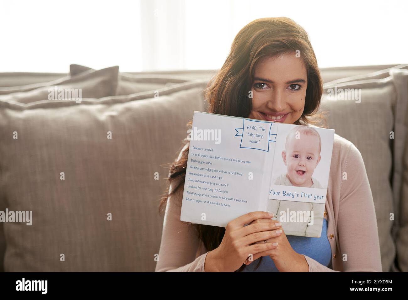 Elle sait à quoi s'attendre. Une jeune femme enceinte lit un livre de bébé à la maison. Banque D'Images