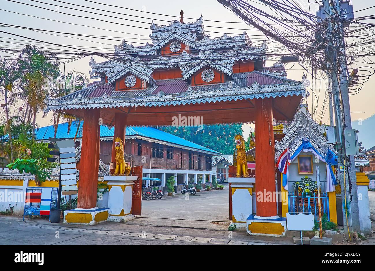 La porte du temple Wat Pa Kham avec des enchevêtrements de fils électriques sur le pôle à côté, Pai, Thaïlande Banque D'Images