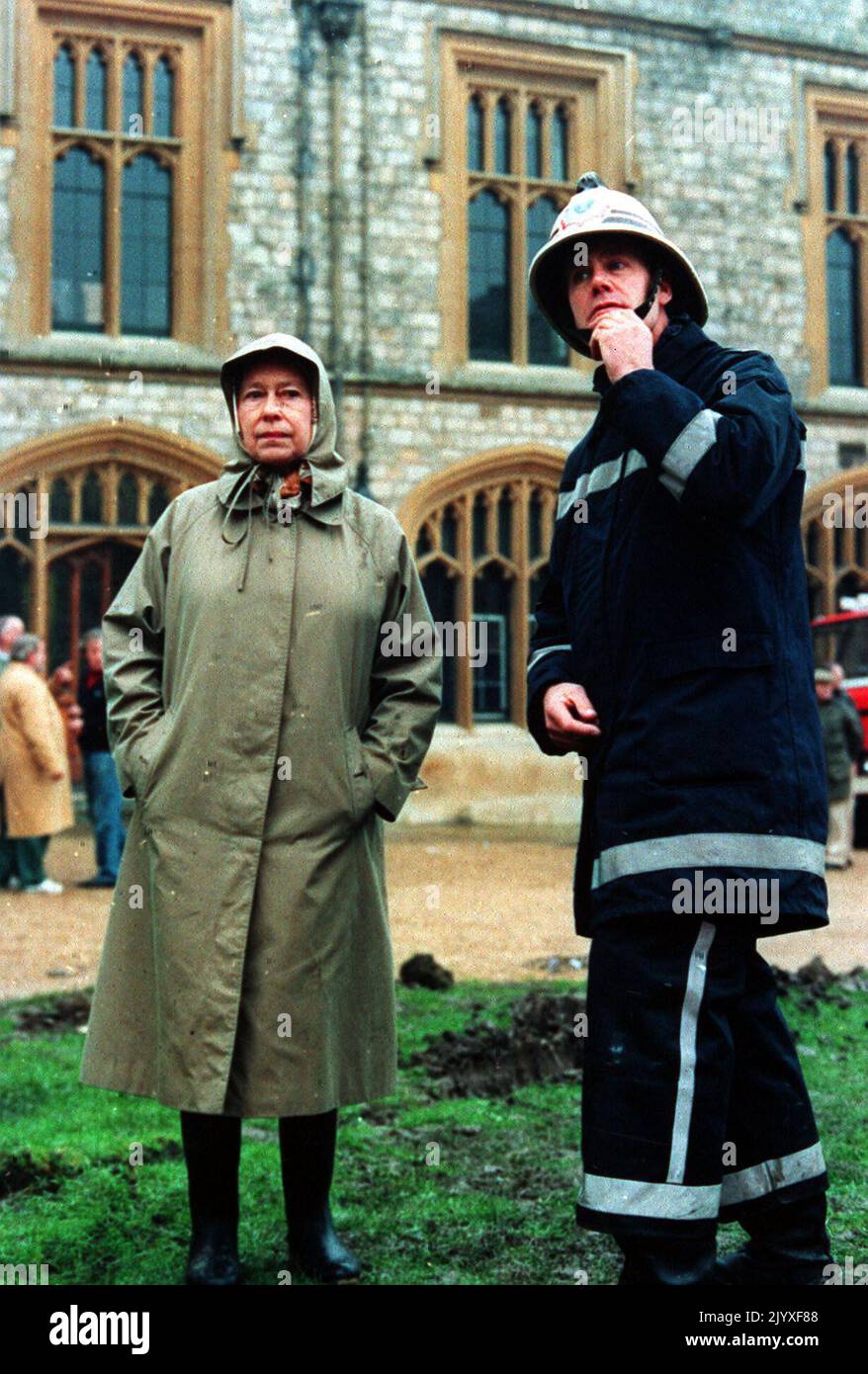 Photo du dossier datée du 21/11/1992 de la reine Elizabeth II inspectant les ruines du château de Windsor avec un pompier. Le discours de la Reine Annus horribilis à Guildhall le 24 novembre 1992, marquant 40 ans sur le trône, suivi d'une année qui avait vu le prince et la princesse de Galles en guerre, le duc et la duchesse de York séparés, la princesse Anne divorcée, Le château de Windsor monta en flammes et la publication du livre d'Andrew Morton : « diana: Her True Story ». En décembre, le prince et la princesse de Galles se sont officiellement séparés. Date de publication : jeudi 8 septembre 2022. Banque D'Images