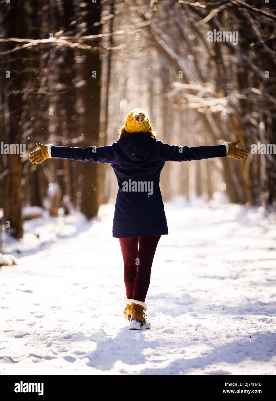 Une femme qui se répand les bras pendant une randonnée dans les bois en hiver au coucher du soleil. Banque D'Images