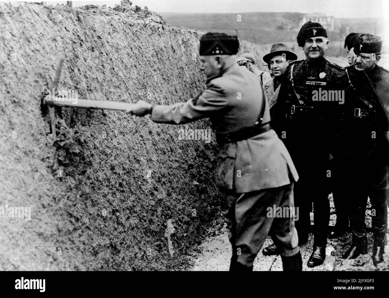 Mussolini effectue des fouilles avec Un Pick-Ax commence des travaux sur le nouvel aérodrome - Signor Mussolini inaugure les travaux d'excavation avec un pick-ax. Signor Mussolini a inauguré avec une hache le travail de construction d'un grand nouvel aérodrome à Magliana Vecchia, près du site choisi pour l'exposition universelle de Rome de 1941. 27 mars 1937. Banque D'Images