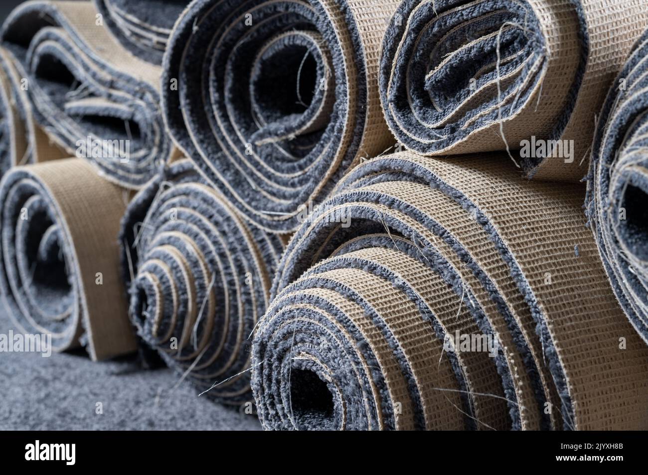 Des vieux rouleaux de tapis empilés dans une chambre grise. Banque D'Images