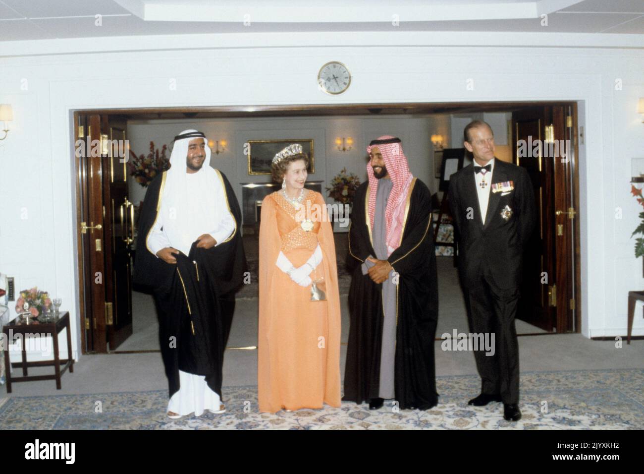 Photo du dossier datée du 24/2/1979 de la reine Elizabeth II porte une robe orange avec des manches de facturations par Ian Thomas comme elle représente une photographie avec Sheikh Zayed bin Sultan Al Nahyan, Chef d'Abu Dhabi et président des Émirats arabes Unis avant le dîner à bord du yacht royal Britannia. Elizabeth II était célèbre pour son amour des couleurs de bloc et des chapeaux assortis et sa mode est devenue une partie légendaire de son rôle de monarque. La Reine a été décrite comme un « habillage de pouvoir dans extremis » pour avoir utilisé des teintes vibrantes pour se démarquer de la foule tandis que ses chapeaux lui ont permis d'être facile Banque D'Images