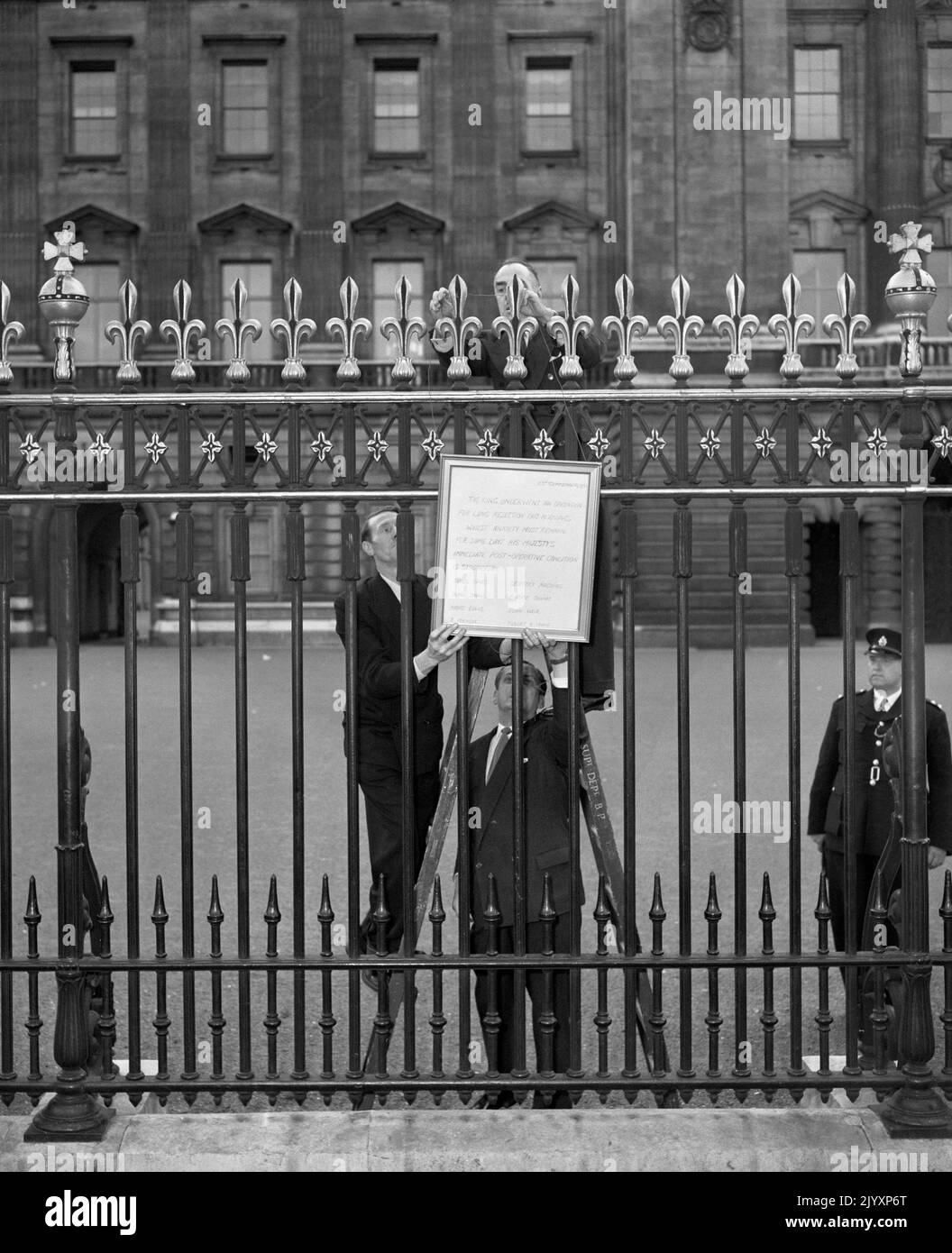 Photo du dossier datée du 23/9/1951 de trois fonctionnaires du Palais affichant un bulletin sur les rails du Palais de Buckingham annonçant que le roi George VI avait subi avec succès une opération pour son état pulmonaire. La mort royale est généralement confirmée par la tradition ancestrale qui consiste à placer un avis en spectacle au palais de Buckingham et dans d'autres résidences royales. Date de publication : jeudi 8 septembre 2022. Banque D'Images