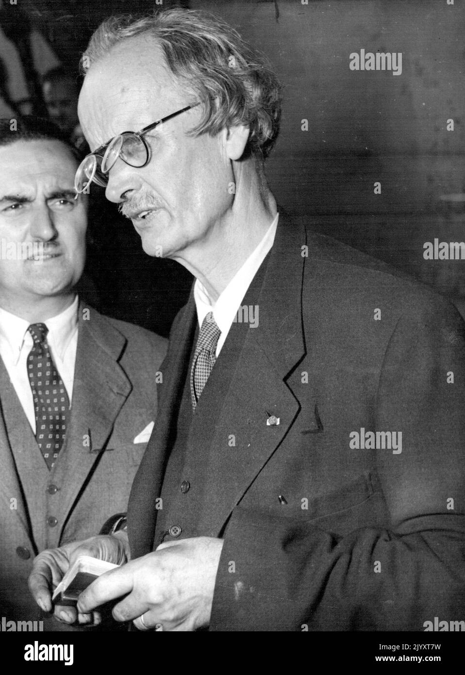 Piccard explique son bathyscape -- lunettes avec une deuxième lentille articulée ***** Une touche de l'étrange pour le professeur Auguste Piccard comme il est photographié à bord du cargo à vapeur Scaldis à Anvers, Belgique, 10 septembre, expliquant ***** Bathyscape aux scientifiques et aux journalistes. Le Bathyscape est une boule d'acier de quarante tonnes, dont la construction a amené Piccard et son assistant Max Cosyns, deux ans à perfectionner. Ils y descendront dans des profondeurs inexplorées du golfe de Guinée, dans les Indes orientales. Suspendue sous un immense flotteur, contenant du pétrole - 'Gasbag' pour le bathyscape - la sphère sera abaissée Banque D'Images