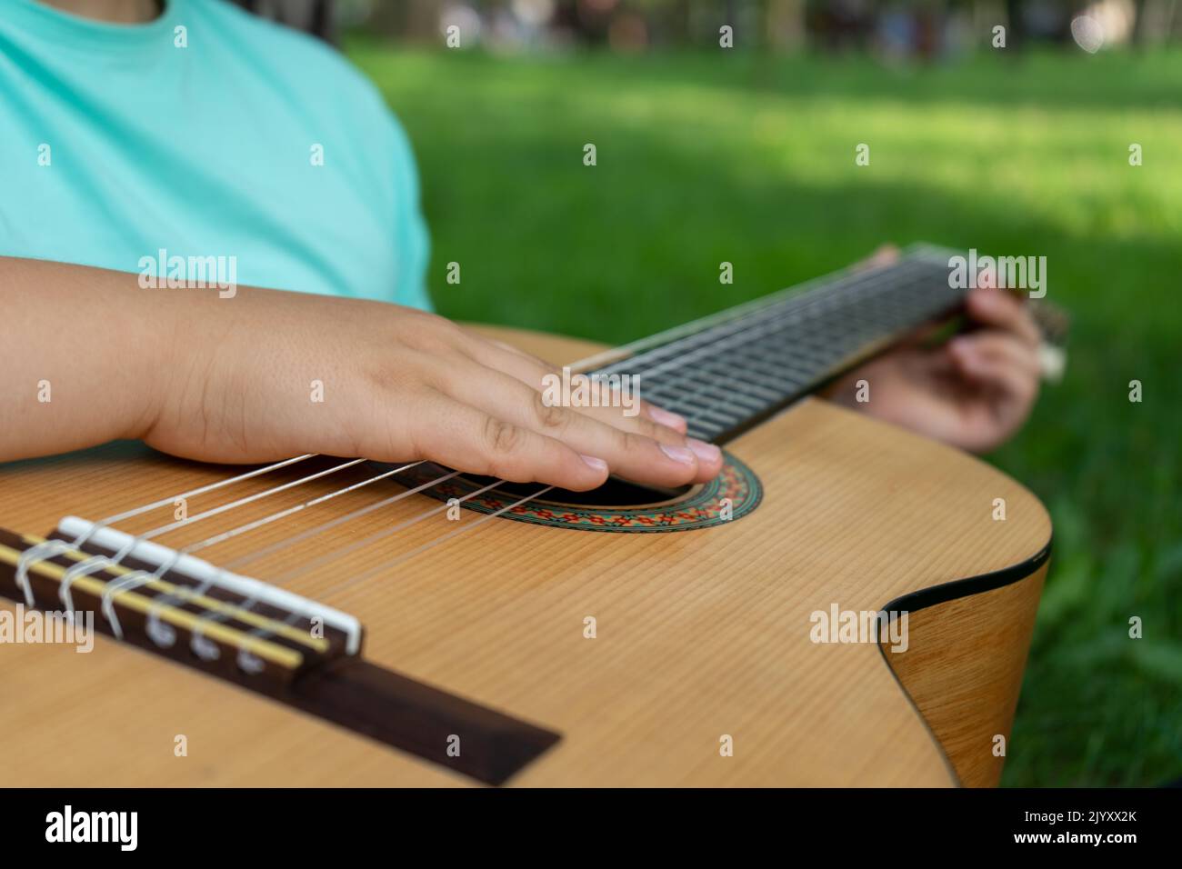 La main du guitariste repose sur les cordes d'une guitare acoustique classique en bois Banque D'Images