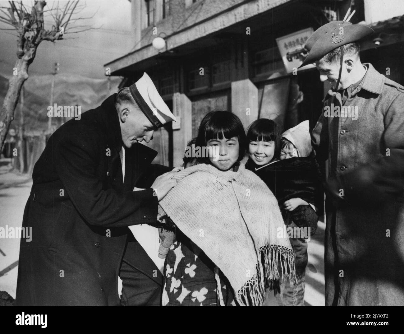 Les troupes d'occupation au Japon ONT COURU Sailor (***** G. Hill East Brisbane) pense qu'il y a quelque chose à dire pour cette façon de porter un bébé. La mère a deux jeunes accrochés à son dos et la fille porte les petites sœurs. Le sergent F. Wilson (Cotterdoe, WA) cherche. 20 mars 1946. (Photo du Telegraph Feature Service, Brisbane). Banque D'Images