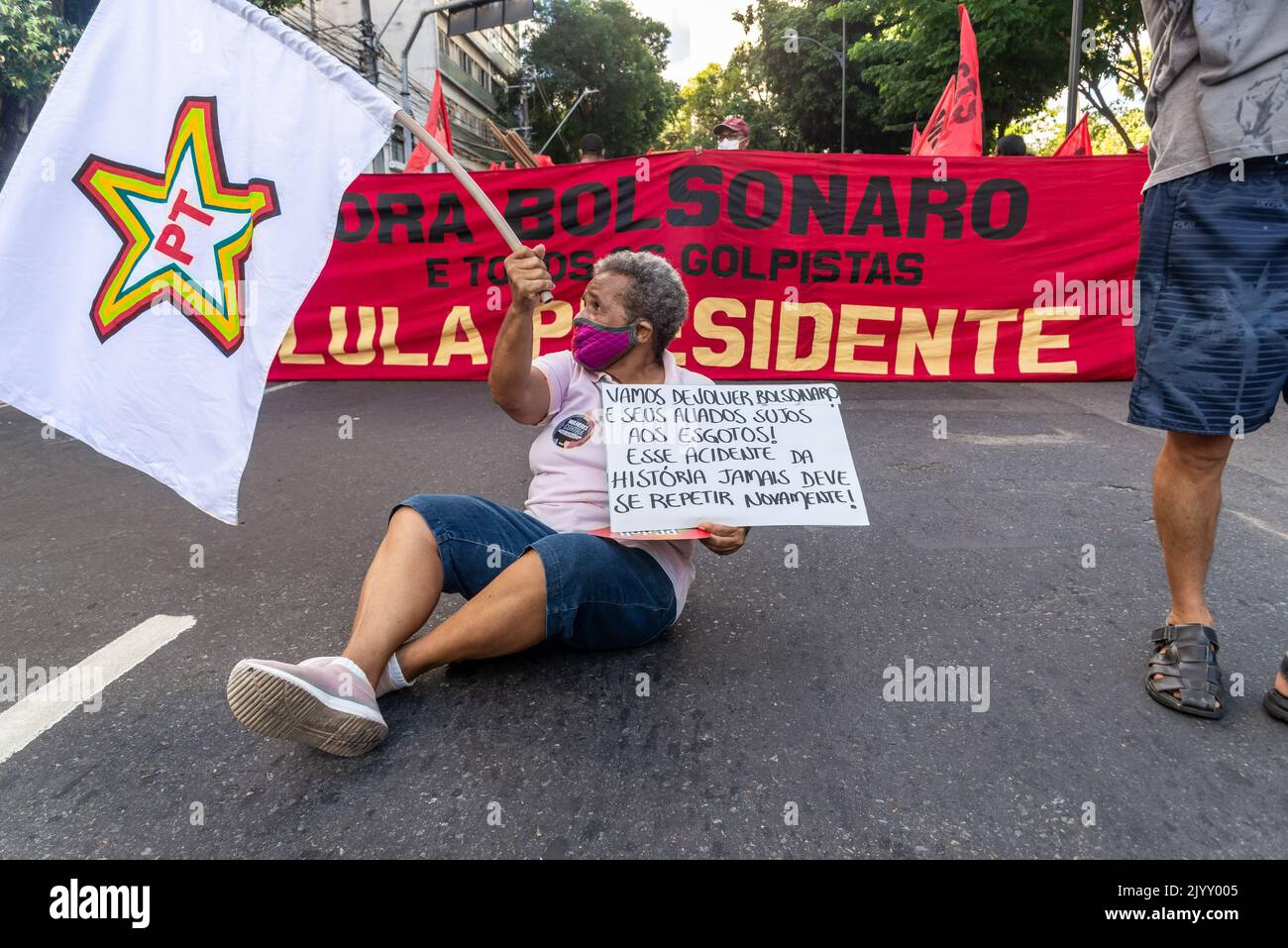 Salvador, Bahia, Brésil - 09 avril 2022: Militant protestant contre le candidat d'extrême-droite à la présidence Jair Bolsonaro, avec un drapeau et une affiche ca Banque D'Images